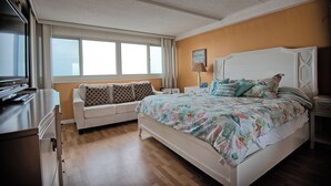Un dormitorio con cama, sofá, mesita de noche y cómoda.