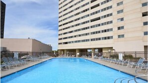 Una piscina con sillas de descanso y un cartel que indica 'No Diving', rodeada de edificios.