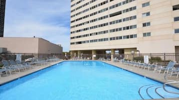 A swimming pool with lounge chairs and a 'No Diving' sign, surrounded by buildings.