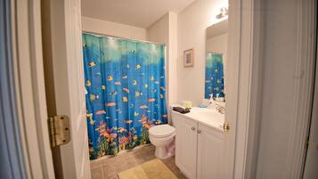 A bathroom with a shower curtain featuring an underwater scene, a toilet, a sink, and a mirror.
