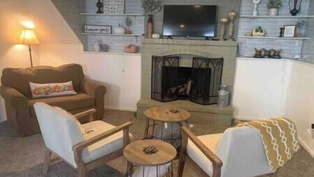 Ett mysigt vardagsrum med en öppen spis, en soffa, två fåtöljer och ett soffbord.