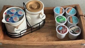 Ett träbricka med en kaffebryggare och flera behållare med kaffekapslar.