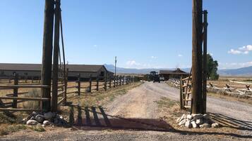 A rustic wooden gate with a sign reading 'Beartooth Cabins' leading to a gravel road.