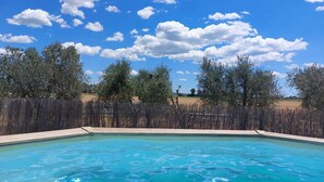 A clear blue swimming pool with a wooden fence and trees in the background. - "Il Frassino" Farmhouse with Pool & Air Conditioning (Campiglia marittima)