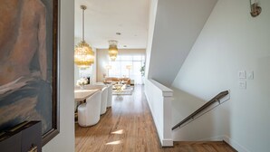 A modern interior with a staircase, a dining area, and a view into another room. - Kirby Haus ·Modern Luxury· West U· RiceVillage · sleeps16 ·EV 🚗🔌 •3900sqft ⭐️⭐️⭐️⭐️⭐️ (Houston)
