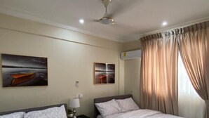 A hotel room with two beds, a ceiling fan, and artwork on the walls. - Exotic 2 Bedrooms Apartment (Accra)