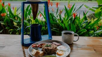 A table with a plate of food, a coffee mug, and a blue coffee maker.