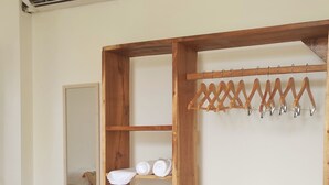 Una habitación con un armario de madera, un perchero y una ventana.