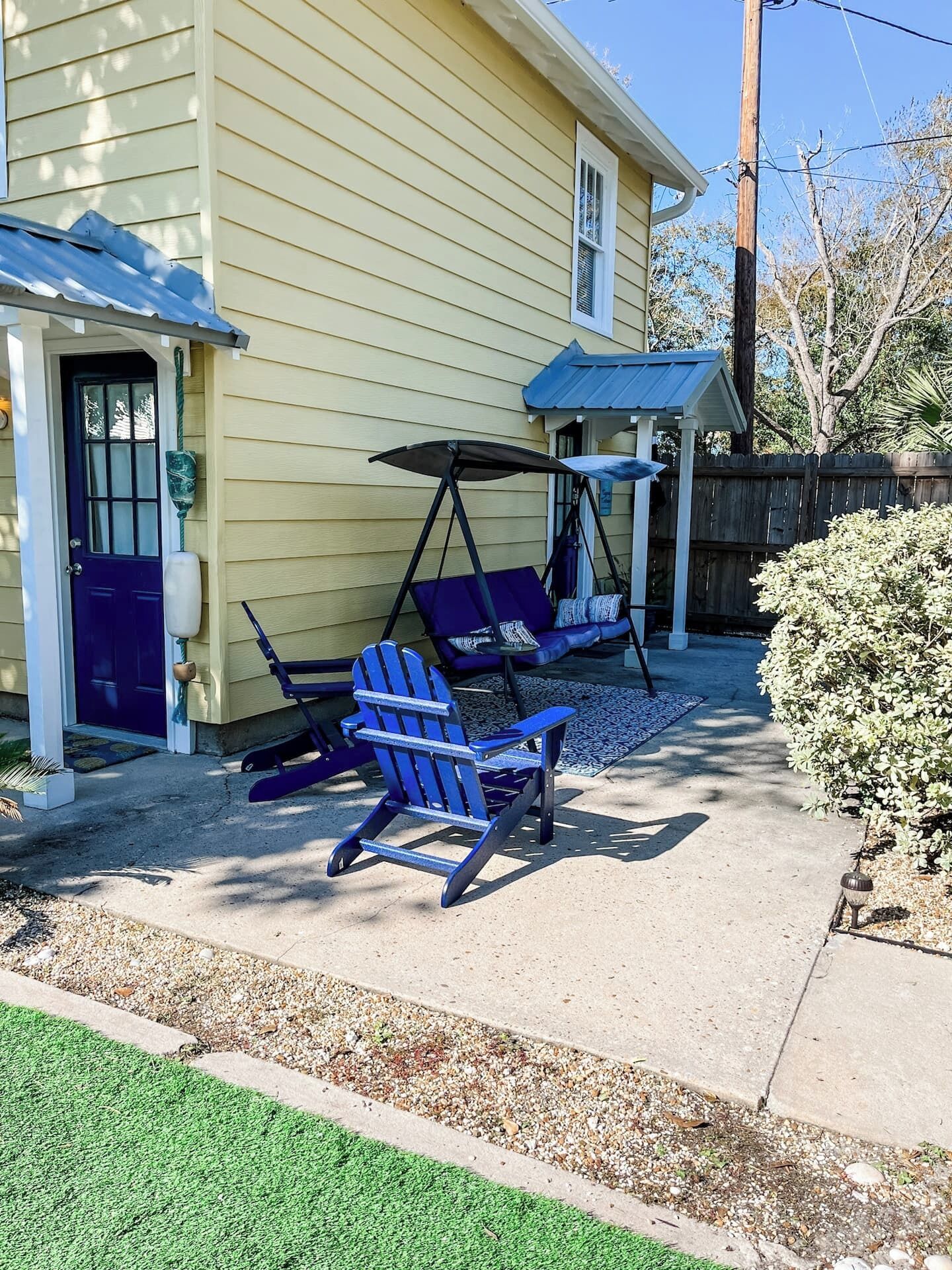 A house with a porch featuring two Adirondack chairs and a swing set.