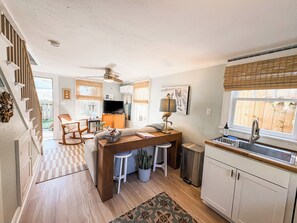 A compact kitchen with a dining area, a built-in stove, and a window with blinds. - Gypsy Cottage · Walkable · Pet-Friendly PSJ (Port St. Joe)