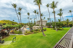 A hotel with a pool, palm trees, and a well-maintained lawn.