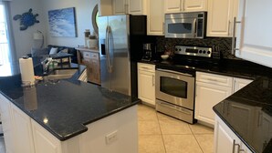 Una cocina moderna con armarios blancos, electrodomésticos de acero inoxidable y una encimera de granito negro.