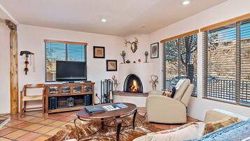Cozy living room with a fireplace, sofa, armchairs, flat-screen TV, and coffee table.