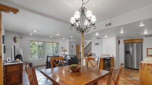 A spacious kitchen with a wooden dining table, chairs, a chandelier, and a refrigerator. - Fort Marcy 95 | Walk to Plaza | Kiva Fireplace | Full Kitchen | Hot Tub | Pool | End Unit | 2 Levels (Santa Fe)