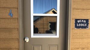A brown wooden door with a window and a keypad lock. A sign on the wall reads "Bear Lodge."