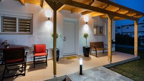 A covered outdoor seating area with a wooden pergola, a bench, and two chairs. - Villa Christalia. Cozy family Villa 300m from the beach with swimming pool. (Κολύμπια)