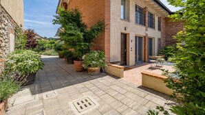 Un patio con un sendero empedrado, plantas en macetas y una zona de estar con mesas y sillas.