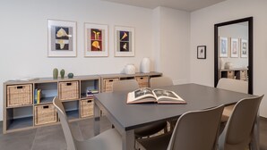Un comedor moderno con una mesa larga, sillas y una estantería con cestas de mimbre.