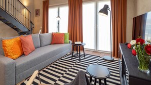 A living room with a grey sofa, a black and white striped rug, a small round table, and a vase of flowers. - Bright Farmhouse Loft near Lake Maggiore and Orta (Cressa)