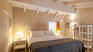 A bedroom with a bed, bedside lamps, a wardrobe, and a window with curtains. - Bright Farmhouse Loft near Lake Maggiore and Orta (Cressa)