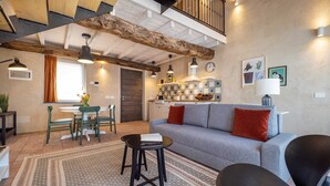 A cozy living room with a sofa, chairs, a coffee table, and a dining area with a table and chairs. - One Bedroom Loft Style Apartment in Restored Farmhouse (Cressa)