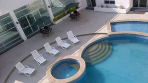 A swimming pool with a hot tub, surrounded by white lounge chairs. - Accommodation with views in Costa del Este 6 (Panama)