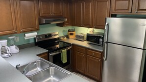 Una cocina con armarios de madera, un refrigerador de acero inoxidable, un microondas, un tostador y un lavaplatos.