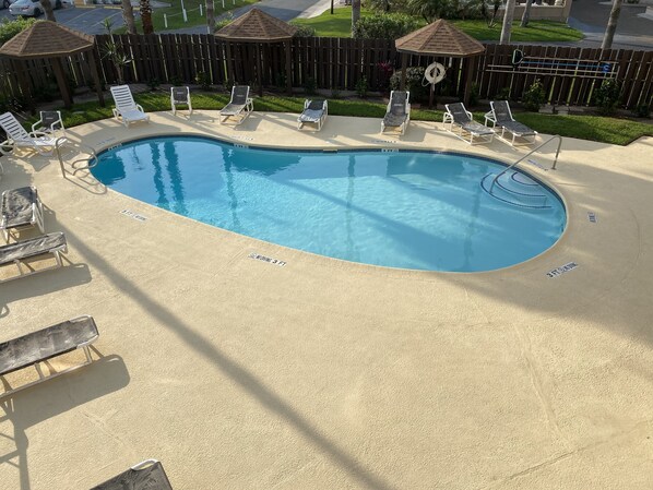 Une piscine avec des chaises longues et une cl ôture en bois en arrière-plan.