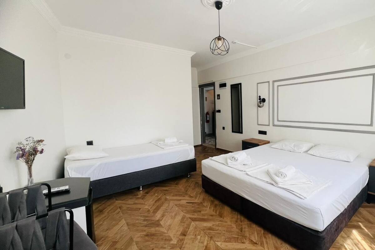 A hotel room with two single beds, a desk, and a chair.