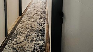Un pasillo con piso alfombrado, una puerta identificada con el número '103', y una pared con un letrero que indica '104'.