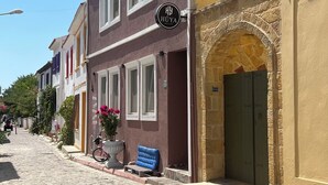 Una estrecha calle adoquinada flanqueada por edificios tradicionales, un cartel de 'HÜYA' y un arco de piedra.