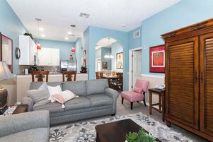 A living room with a grey sofa, a patterned rug, and a wooden cabinet.