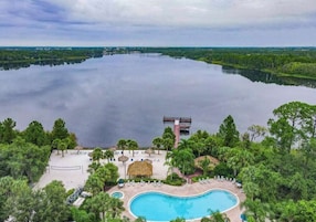 A resort with a large swimming pool, a beach area, and a view of a lake.