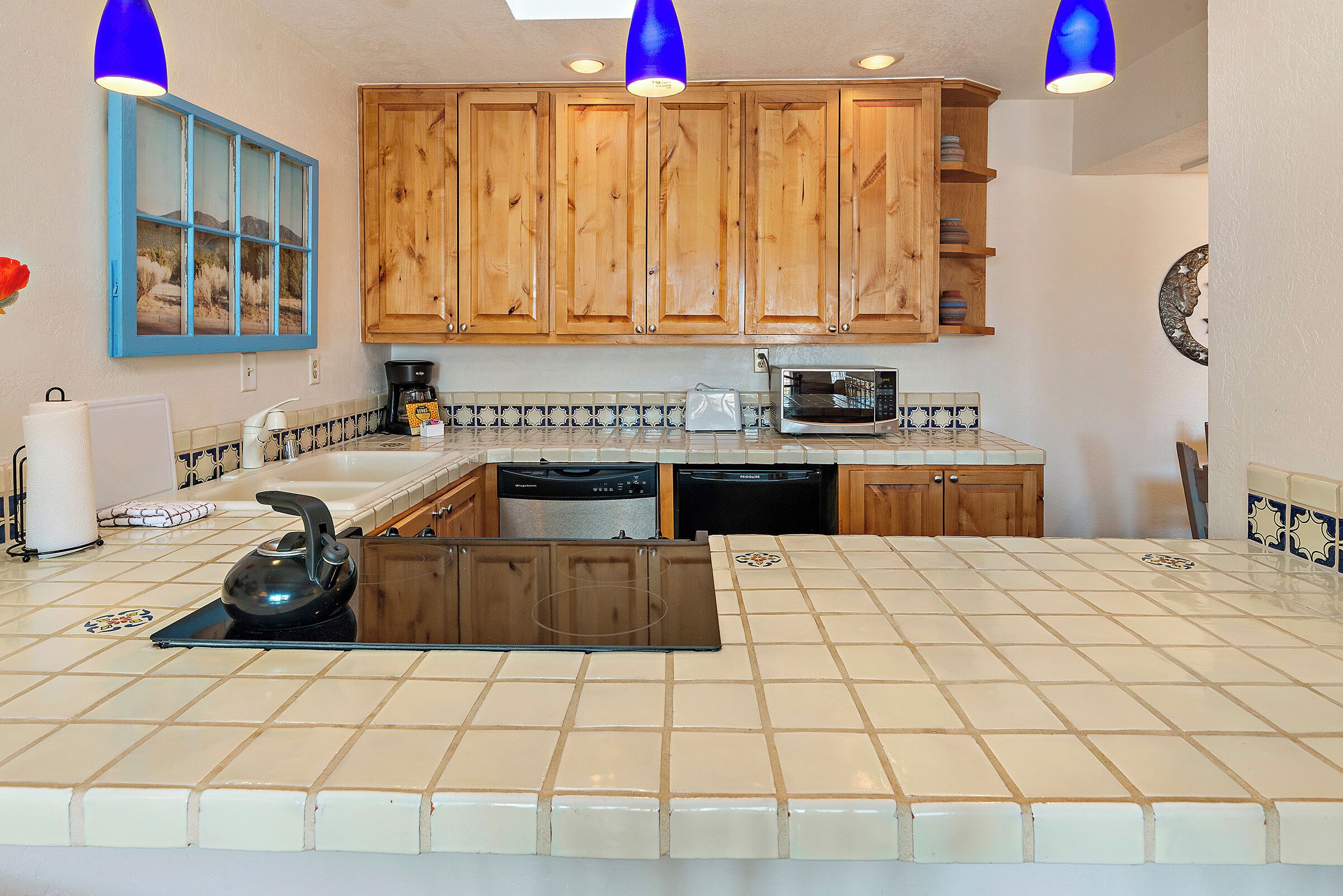 Een keuken met houten kastjes, een magnetron en een waterkoker op het aanrecht.
