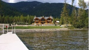 Un chalet doté d’une jetée qui s’avance sur un lac, entouré de montagnes boisées.