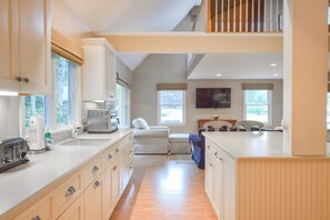 A spacious kitchen with modern appliances, a dining area with a high table, and a view of the outdoors. - Short Walk to Private Beach! (West Yarmouth)