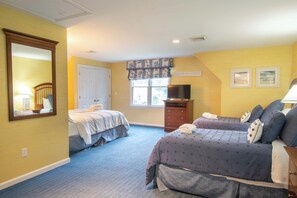 A hotel room with two beds, a dresser, a television, and a window with a view.