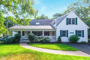 A two-story house with a porch, a covered front entrance, and a brick pathway leading to the front door.