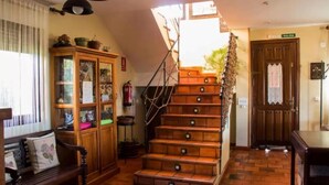 Una escalera conduce a un rellano con un banco de madera y un armario con puertas de cristal.