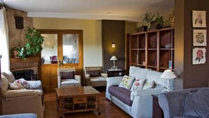 Una sala de estar acogedora con chimenea, dos sillones, un sofá y una mesa de centro.
