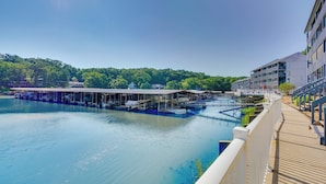 A waterfront hotel with a covered dock area, a pool, and a view of the surrounding greenery.