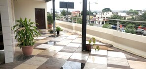 A tiled balcony with potted plants, a door, and a view of the cityscape. - NCG Comegua 1 (Guayaquil)