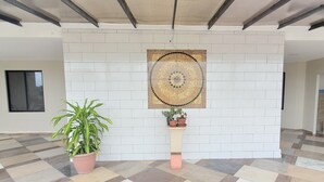 Una habitación con suelo de baldosas, una planta en maceta, un adorno en la pared y una ventana.