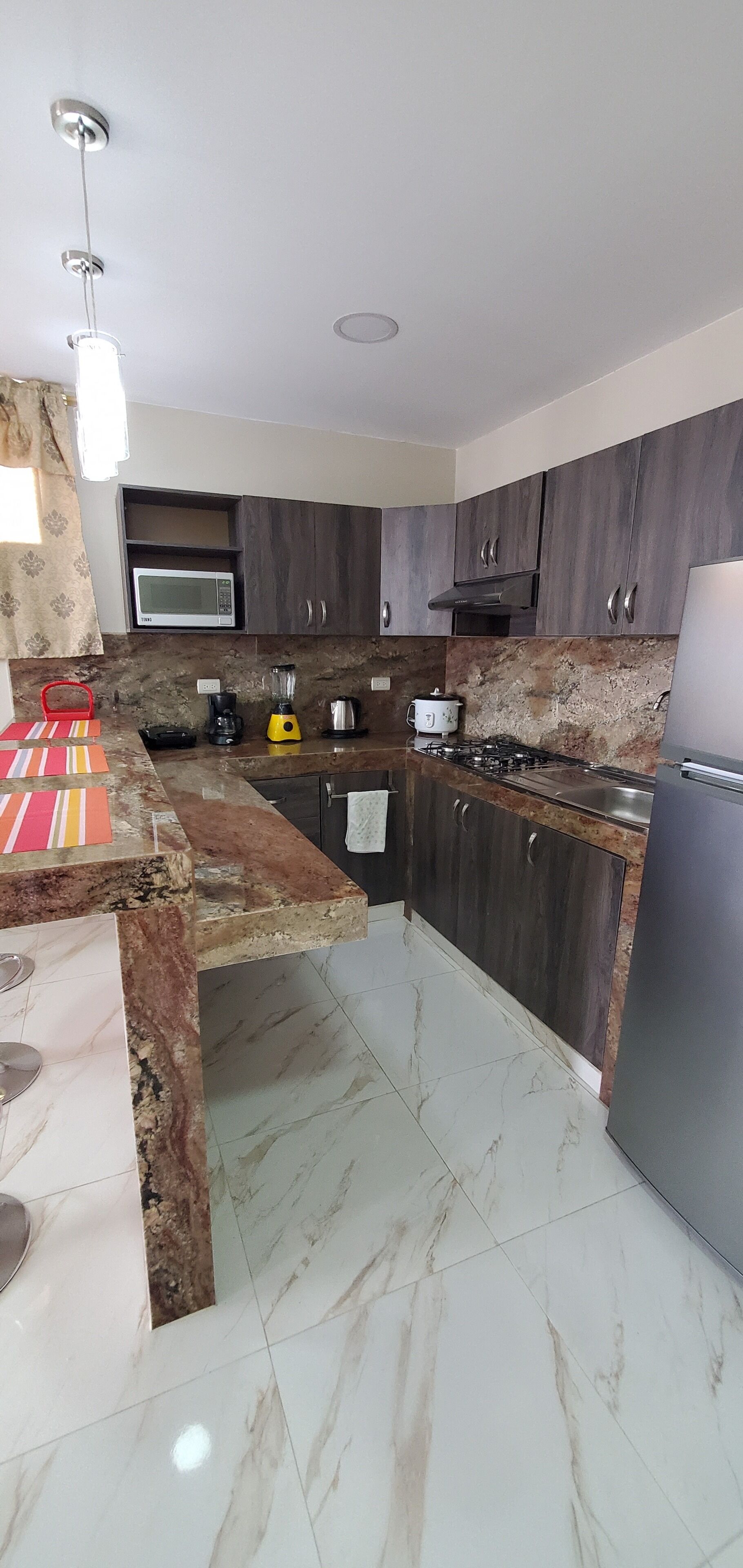 A modern kitchen with dark wood cabinets, a built-in microwave, a gas stove, and a stainless steel sink.