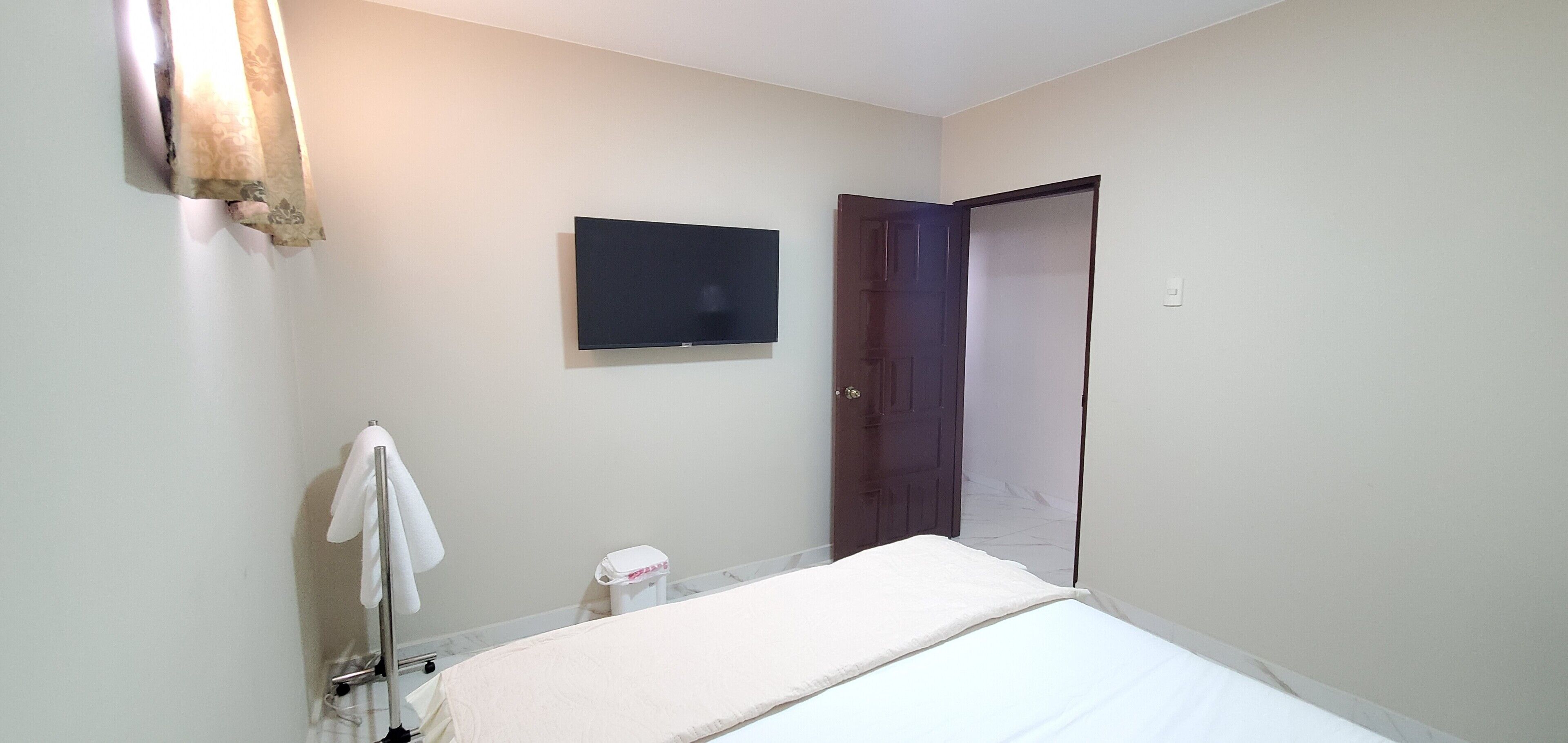 A bathroom with a bed, a towel rack, a toilet, a mirror, and a door.