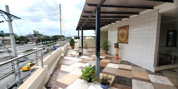 A balcony with a checkered floor, potted plants, and a view of the street. - NCG Comegua 1 (Guayaquil)