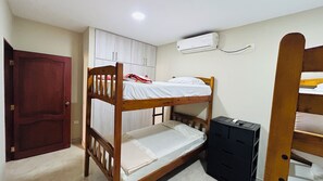 A bunk bed room with a wardrobe, an air conditioning unit, and a desk with a chair. - NCG Comegua 1 (Guayaquil)