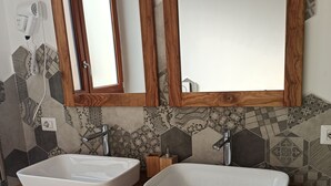 Ein Badezimmer mit zwei weißen Waschbecken, einem Holzkosmetikschrank und einem Spiegel mit Holzrahmen.