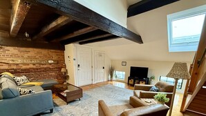 A living room with a sofa, armchair, and a coffee table. There is a brick wall with a sign, a door, and a window. - Superb Location! Heart of Old Port-Spacious Apartment (Portland)
