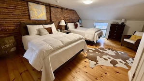 A bedroom with two beds, a brick wall, a cowhide rug, and a wooden floor. - Superb Location! Heart of Old Port-Spacious Apartment (Portland)